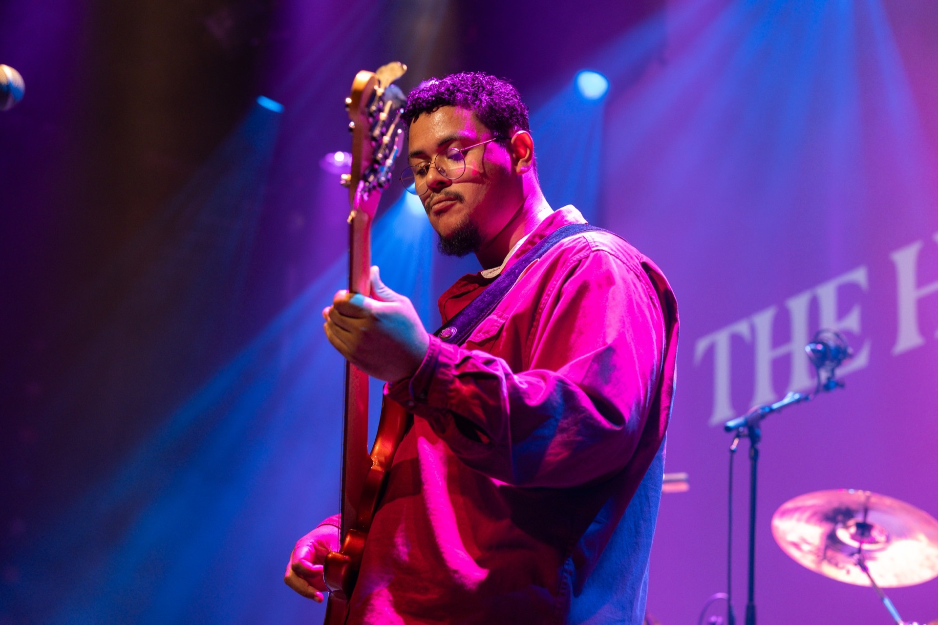 Bassist in magenta stagelicht tijdens een optreden van MusicSoulHouse