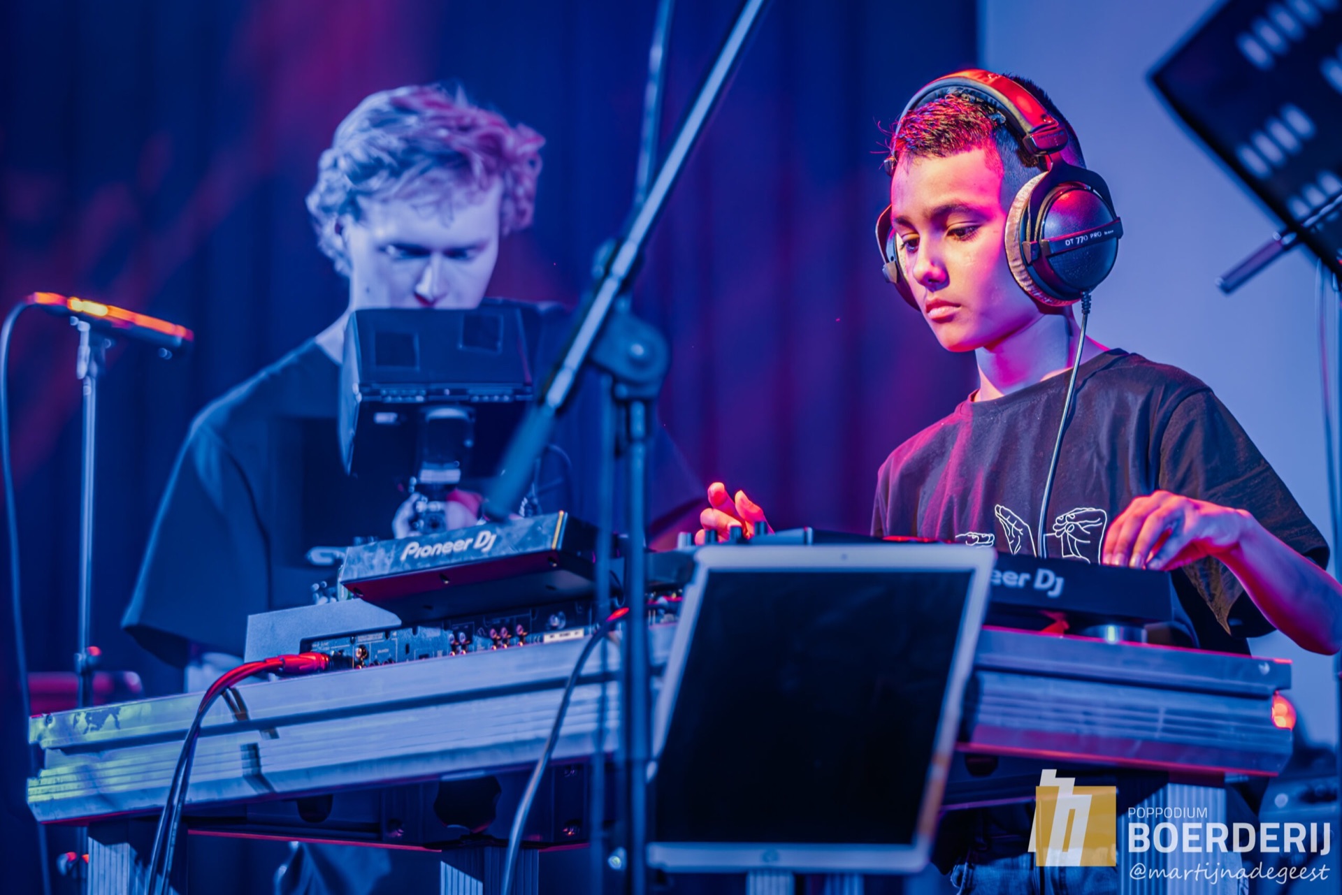 Docent en leerling met koptelefoon achter de dj-set en productieapparatuur
